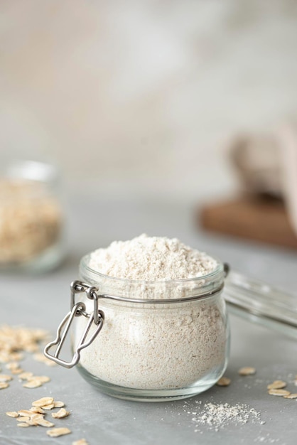 Harina de avena en un frasco de vidrio sobre una mesa blanca