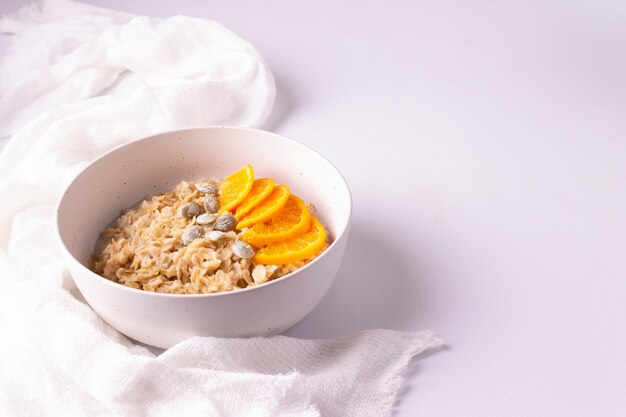 Harina de avena mandarina plato redondo fondo blanco.