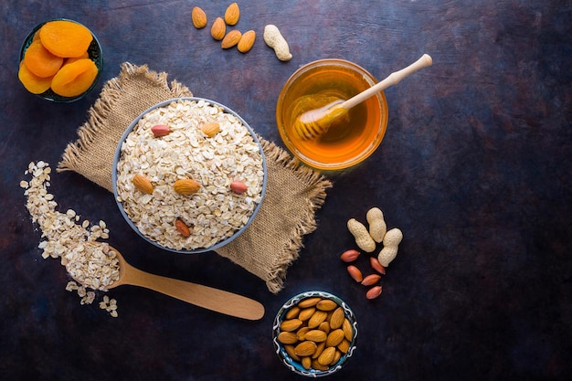 Harina de avena y nueces en burlap Flocos de avena en cuenco y miel Almendas de avena seca y albaricoques secos