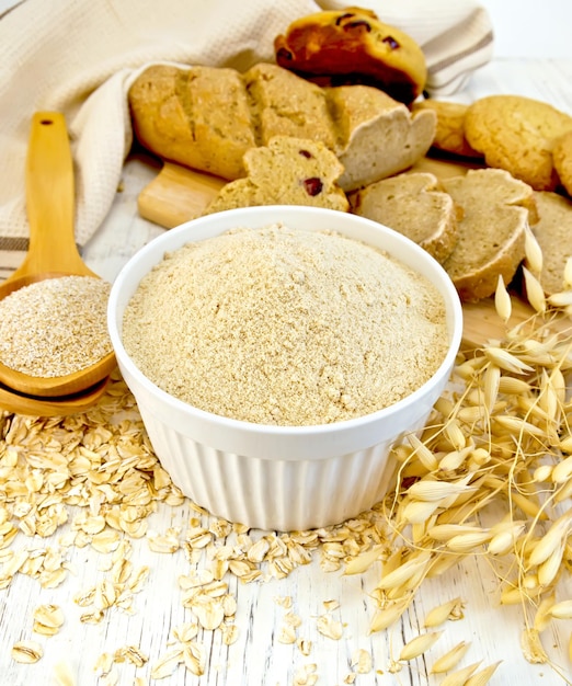 Harina de avena en tazón blanco con salvado en cuchara a bordo