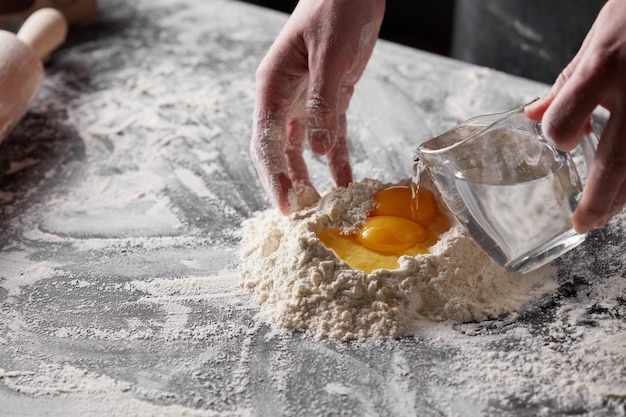 Harina blanca y yema sobre una mesa de cocina oscura