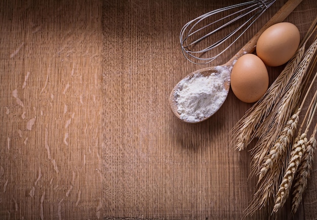 Harina de copyspace organizado en cuchara huevos espigas de trigo corola en tablero de madera comida y bebida bodegón