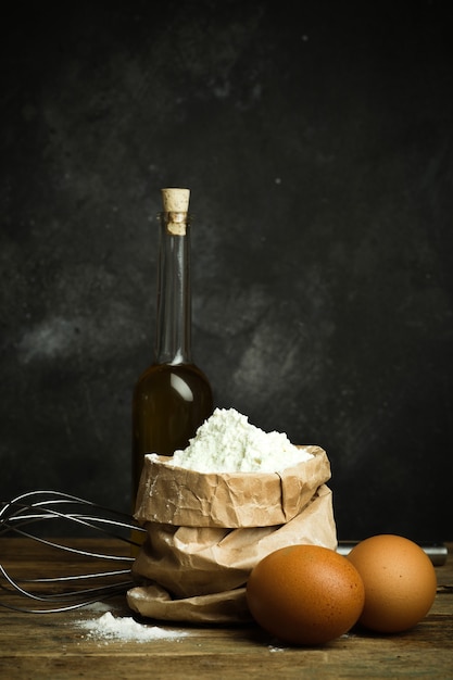 Harina para hornear pan de masa de pizza y pasta en una mesa de madera y fondo oscuro Concepto de cocina casera