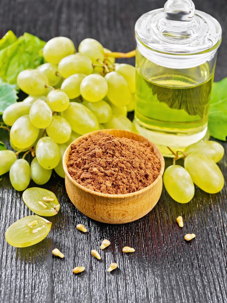 Foto harina de semilla de uva en un recipiente, aceite en un frasco y uvas verdes sobre fondo de tablero de madera
