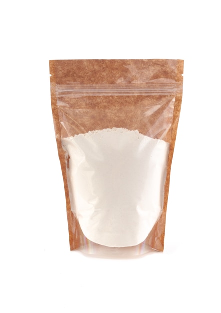 Harina de trigo en una bolsa de papel marrón. Doy-pack con ventana de plástico para productos a granel. De cerca. Fondo blanco. Aislado.