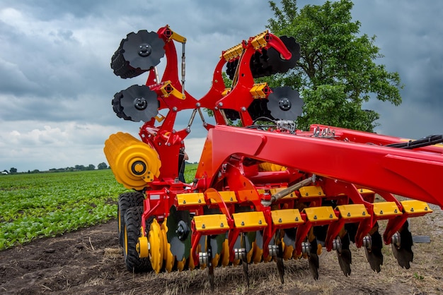 Harrowcultivator de pie cerca de un campo de remolacha verde exposición de tecnologías agrícolas