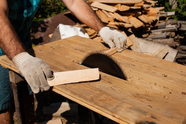 Hart arbeitender Holzarbeiter, der Holzbretter schneidet, Fokus auf Säge