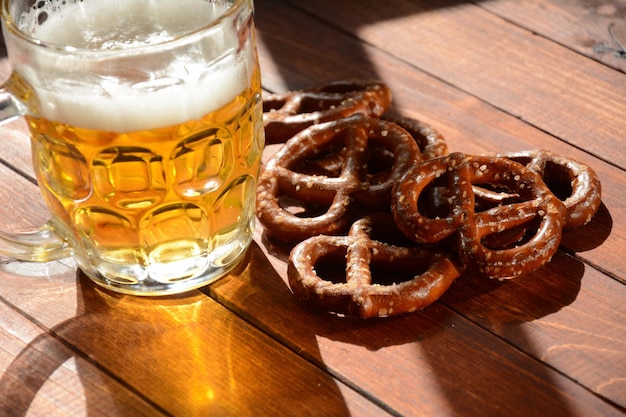 Harte Brezeln oder gesalzene Brezeln Snack für Party auf rustikalem Holztisch mit einem Glas Bier