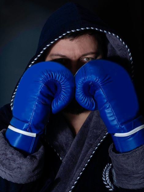 Harter männlicher Boxer posiert in Boxhaltung vor dunklem Hintergrund Professioneller Kämpfer bereit für Boxkampf