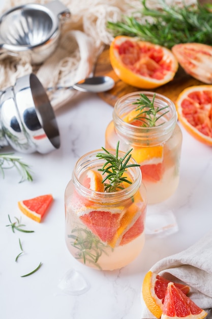 Harter Selterscocktail mit Grapefruit, Rosmarin und Eis auf einem Tisch. Sommer erfrischendes Getränk, Getränk auf einem weißen Tisch
