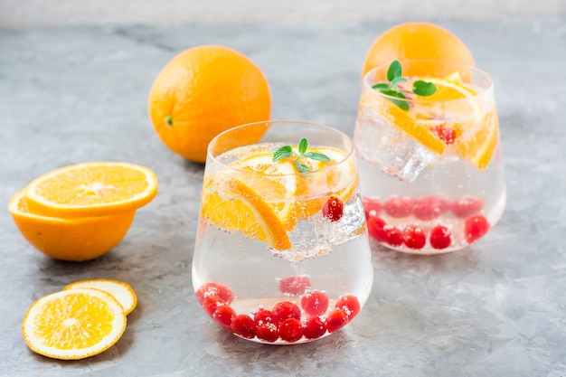 Harter Seltzer Cocktail mit Orange, Cranberry und Minze in Gläsern auf dem Tisch