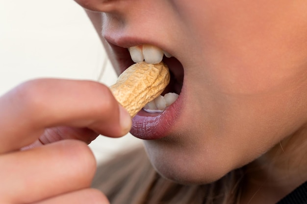 Hartes Erdnuss essen In der Schale starke weiße Zähne beißen eine Nuss ein offener Mund mit einer Erdnuss knacken die Erdnussschale