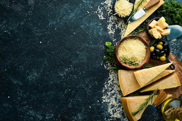 Hartkäse mit Oliven und Käsemesser auf schwarzem Steinhintergrund Parmesan Draufsicht Freier Platz für Ihren Text