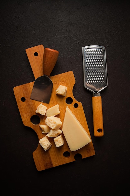 Hartkäse Parmesan auf einem Schneidebrett Käsemesser Reibe Draufsicht keine Menschen