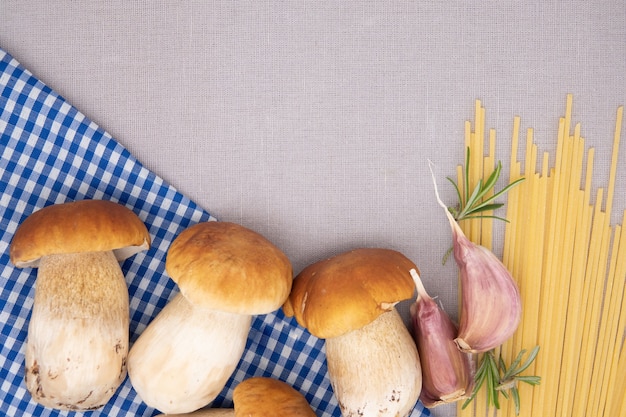 Hartweizen-Tagliolini und frische Steinpilze auf Holztisch