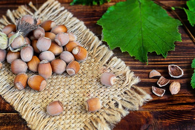 Haselnüsse auf einem hölzernen Hintergrund mit grünen Blättern. Enthält nützliche Vitamine und Mineralstoffe.