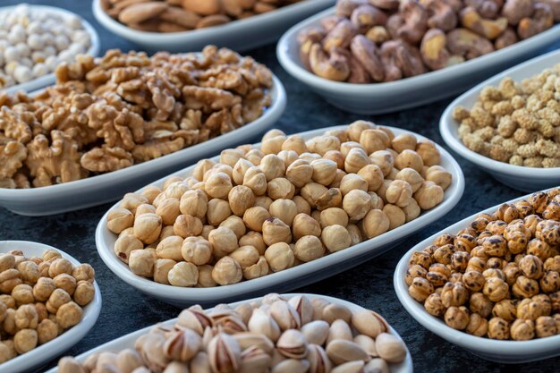 Haselnüsse im selektiven Fokus Nüsse auf dem Teller auf dunklem Hintergrund Walnuss-Kichererbsen Weiße Kichererbsen Trockene Maulbeer-Mandel-Cashew-Pistazien Arten von Nüssen auf dem Teller