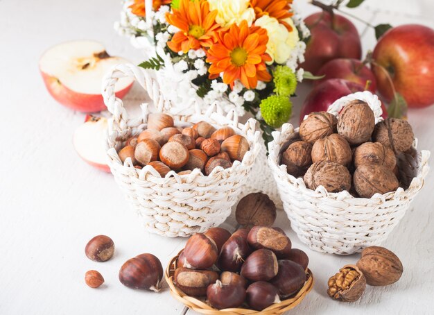 Haselnüsse, Walnüsse und Kastanien mit Äpfeln und herbstlichem Bouquet