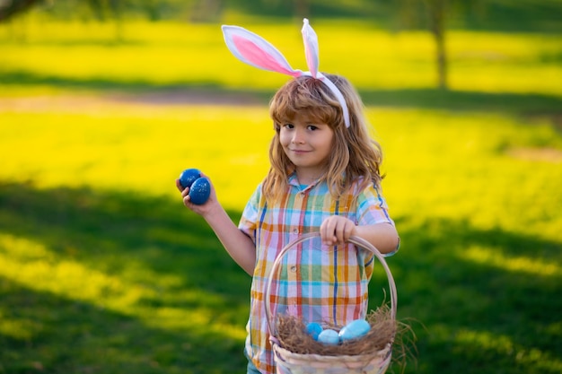 Hasenjunge, Junge, der Ostereier jagt, süßes Kind im Hasenkostüm mit Hasenohren, das Ostern in …