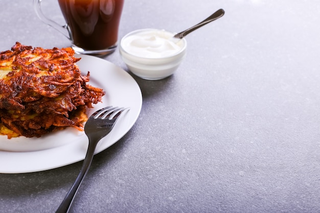 Hash brown y crema agria en un plato sobre un fondo de piedra gris