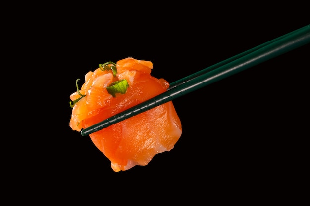 Hashi halten Sushi und Rollen isoliert über schwarzem Hintergrund