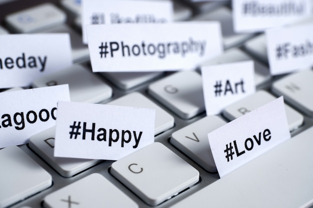 Hashtags populares impresos en papel blanco insertados en el teclado.