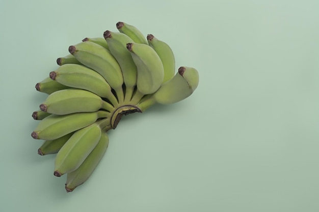 Haufen asiatischer Bananen oder kultivierter Bananen auf grünem Hintergrund mit Kopierraum