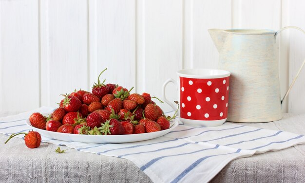 Haufen Erdbeeren auf einem Teller, Stillleben mit reifen roten Beeren und Gerichten.