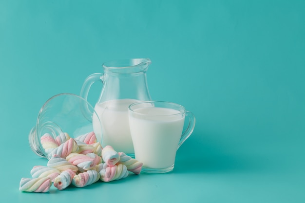 Haufen farbiger verdrehter Marshmallow mit Glas Milch