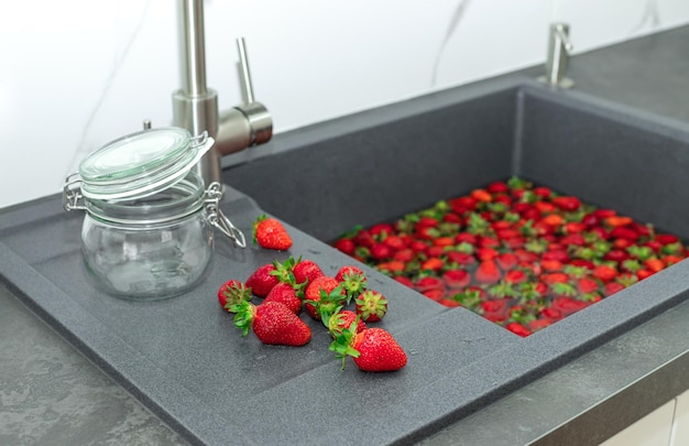 Haufen frischer Erdbeeren und leeres Glas in der modernen Küche