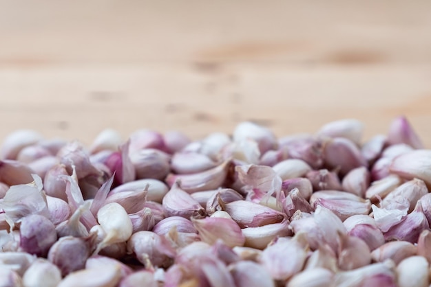 Haufen frischer Knoblauchzehen mit Schale auf Holztisch