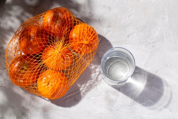 Haufen frischer Mandarinen und Glas mit Wasser auf dem Betontisch