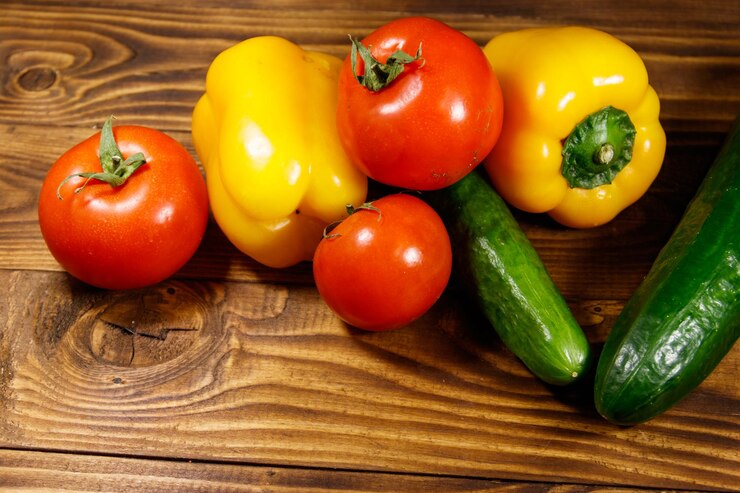 Foto haufen frisches gemüse auf dem küchentisch. reife tomaten, paprika und gurken auf holzhintergrund