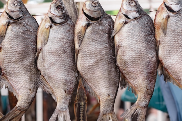 Haufen gesalzener getrockneter Fisch auf Schnur auf dem Markt. Traditionelles russisches Essen. Selektiver Fokus