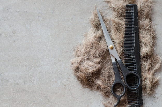 Haufen geschnittener Haare, Schere für Haarschnitte und Kamm. Werkzeuge für Haarschnitte.