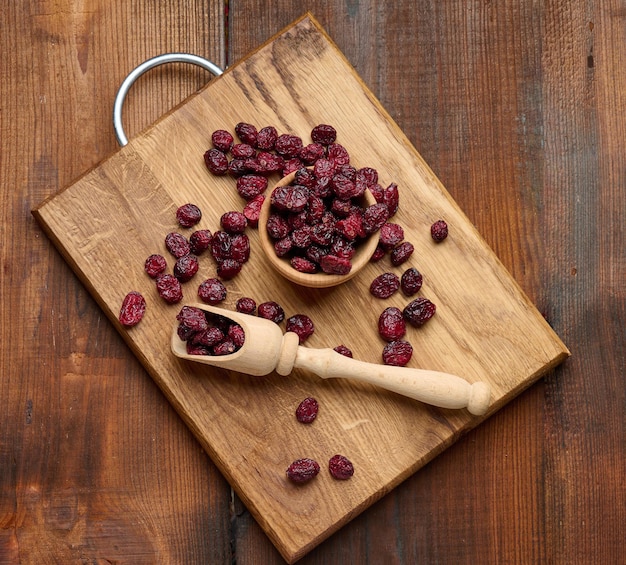 Haufen getrockneter Preiselbeeren in einem Holzlöffel auf einem braunen Tisch. Köstliche Beere, Draufsicht