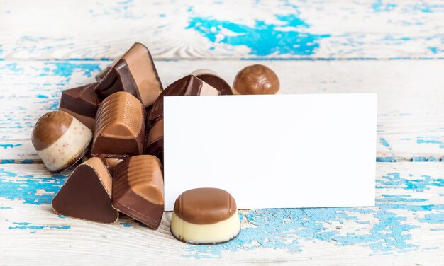 Foto haufen pralinen mit leerer weißer karte auf dem alten blauen tisch. grußkarte.