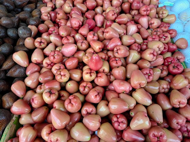 Haufen süßer roter Wasserguavenfrüchte mehrere Früchte auf Holztisch auf natürlichem Hintergrund zum Verkauf im Obstladen