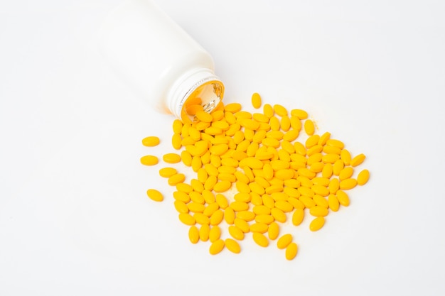 Haufen von gelben Vitaminpillen auf weißem Hintergrund