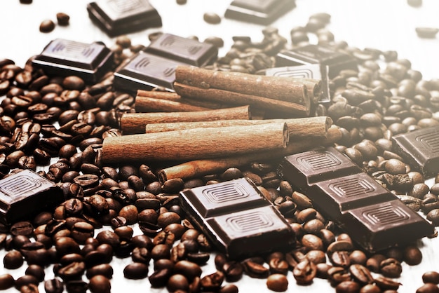 Haufen von gerösteten Kaffeebohnen, Zimtstangen und dunkler Schokolade