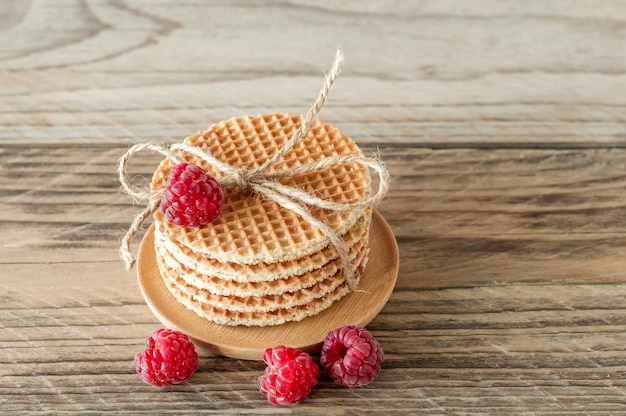 Haufen von Karamell runden holländischen Waffeln mit Himbeeren auf Holztisch.