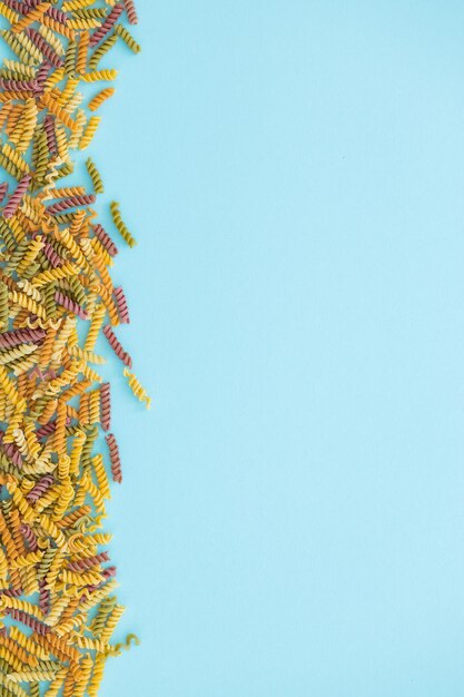 Haufen von Nudeln verschiedene Farben Farfalle-Teigwaren auf Draufsicht des blauen Hintergrundes