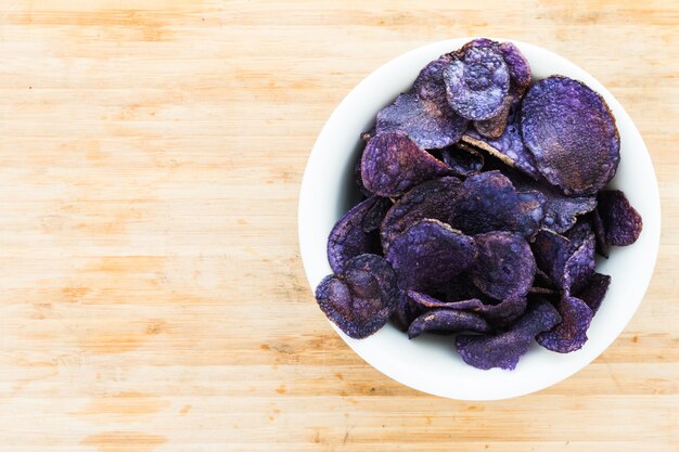 Haufen von purpurroten Kartoffelchips auf hölzernem Hintergrund