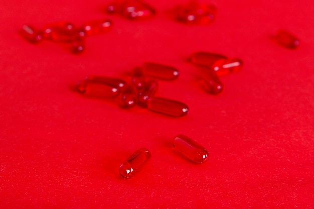 Haufen von roten Pillen auf farbigem Hintergrund Tabletten auf einem Tisch verstreut Haufen von roten Weichgelatinekapsel Vitamine und Nahrungsergänzungsmittel Konzept