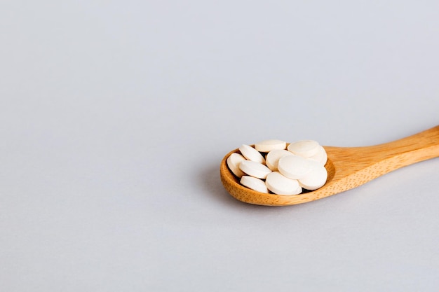 Haufen von weißen Pillen auf farbigem Hintergrund Tabletten auf einem Tisch verstreut Stapel von roten Weichgelatinekapseln Vitamine und Nahrungsergänzungsmittel Konzept