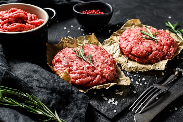 Haupthandgemachte rohe gehackte Rindfleischsteakburger. Bio-Fleisch vom Bauernhof. Schwarzer Hintergrund. Ansicht von oben