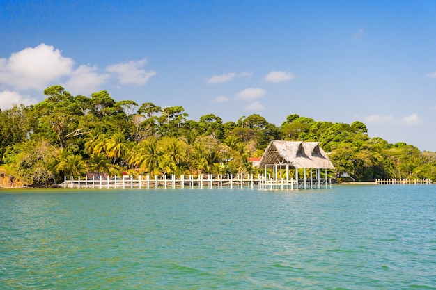 Haus aus Holz und Gras am tropischen Strand in Guatemala, Santo Tomas. Hütte am Meer am sonnigen blauen Himmel. Sommerurlaub auf der Insel. Fernweh, Abenteuer und Entdeckung.