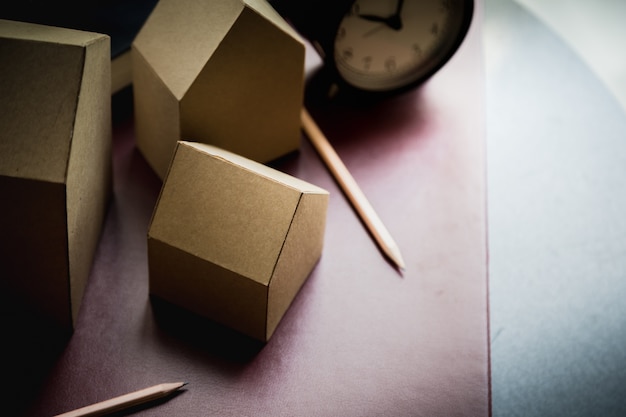 Haus Karton Modell mit Buch und Wecker mit Unschärfe Hintergrund