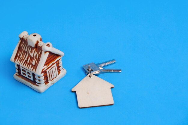 Foto haus und schlüssel mit schlüsselbund auf blauem hintergrund, verkauf und kauf einer wohnung.