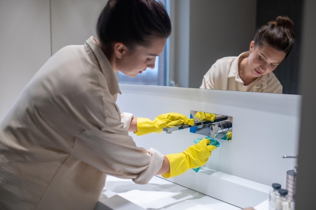 Hausarbeit. Eine junge Hausfrau, die im Badezimmer putzt